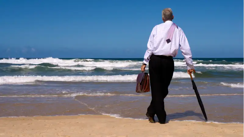 Business man or senior businessman dreaming of retirement on a sandy tropical beach