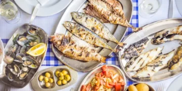Barbecued sea bass, golden, horse mackerel accompanied with tomato salad, clams, bread and white wine