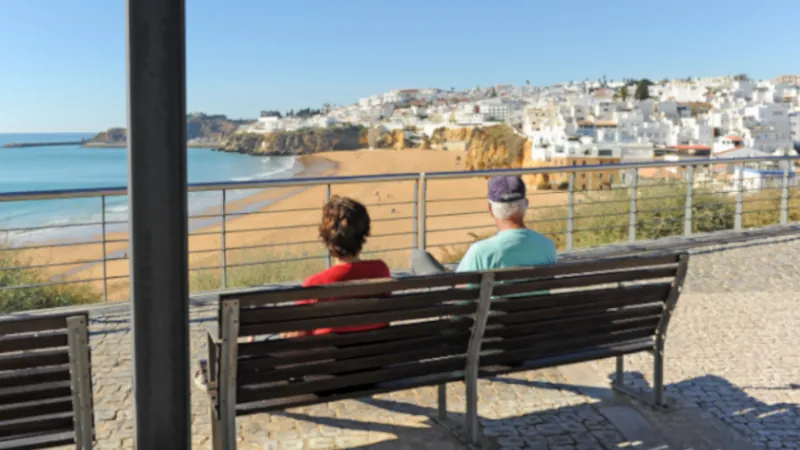 Two elderly tourists sitting on a bench in the beach of Albufeira, one of the most visited by European tourism. Algarve, south of Portugal.