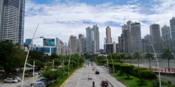 Panama City’s Avenida Balboa with cars on a coastal highway, lined with green parks and modern high-rise buildings under a partly cloudy sky.