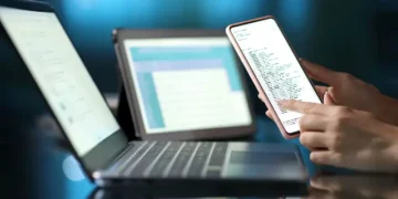 Woman hand using multiple devices at home in the night