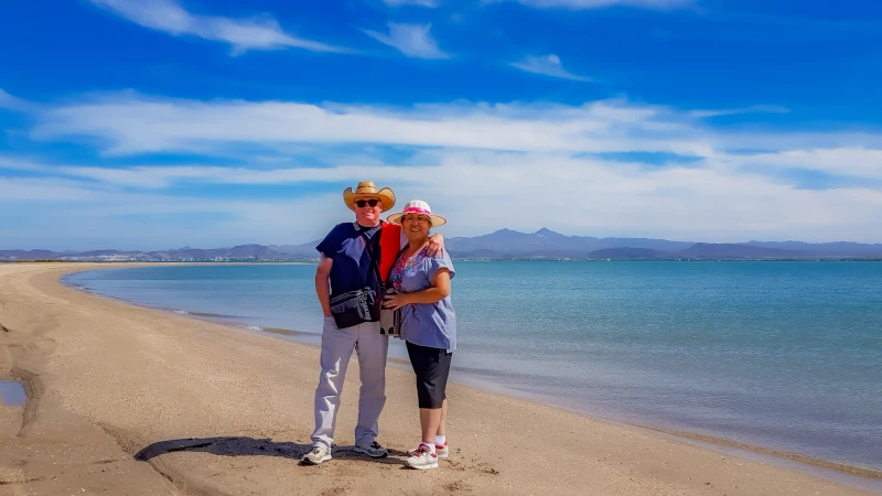 Senior adult couple standing on beach sand with Gulf of Sea of Cortez in La Paz, Baja California Sur Mexico