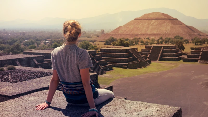 Young woman sitting on the top of pyramid overlooking Teotihuacan