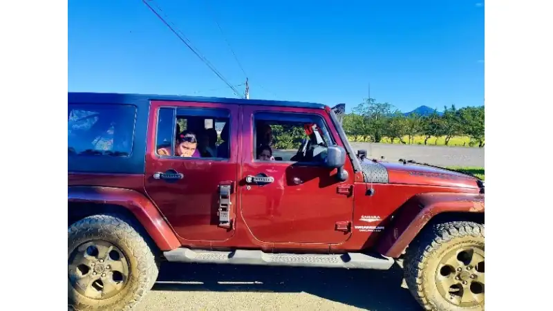 red off-road vehicle parked by the roadside, with a few children visible inside