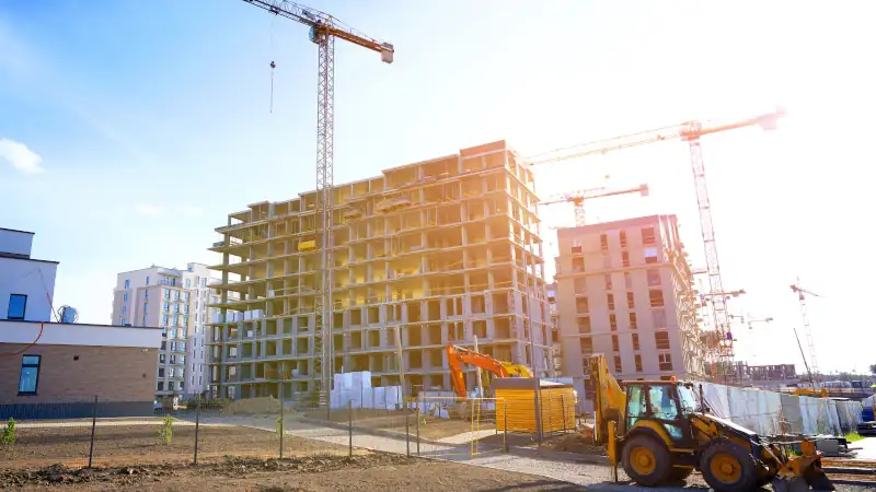 Construction site in modern urban area with cranes and machinery working.