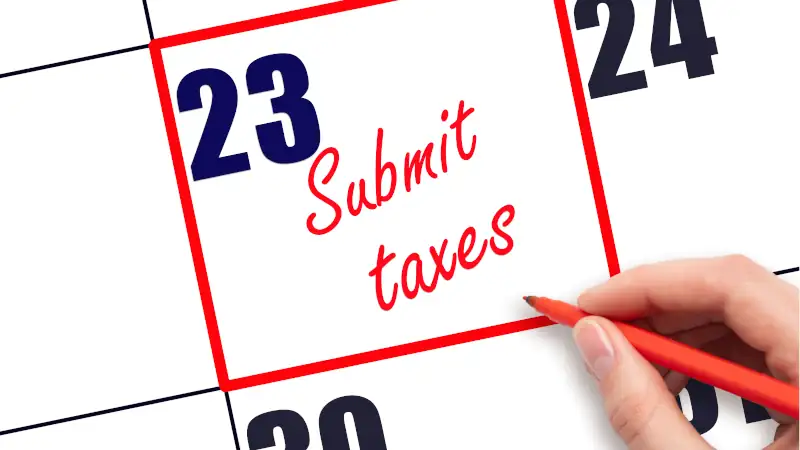 Hand writing Submit taxes reminder and drawing red frame on calendar with red pen on white background.