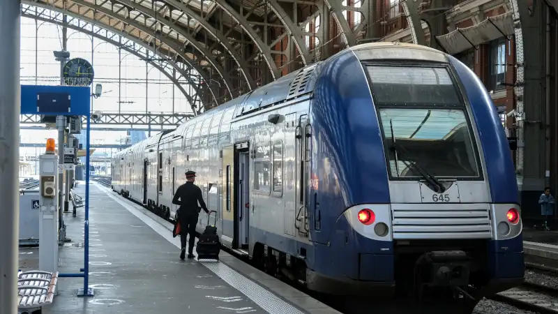 SNCF train driver walks along platform to take duty on a regional train inside a historic railway station in France.