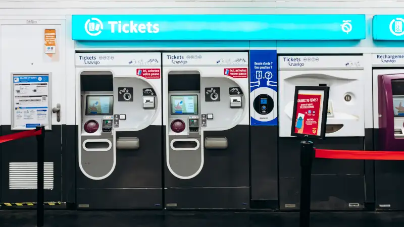 Ticket machines for purchasing and recharging metro tickets and Navigo passes inside a Paris Metro station, with bright signage and modern design.