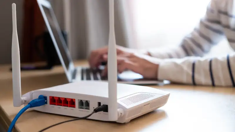 Internet router on working table with blurred man connect the cable at the background