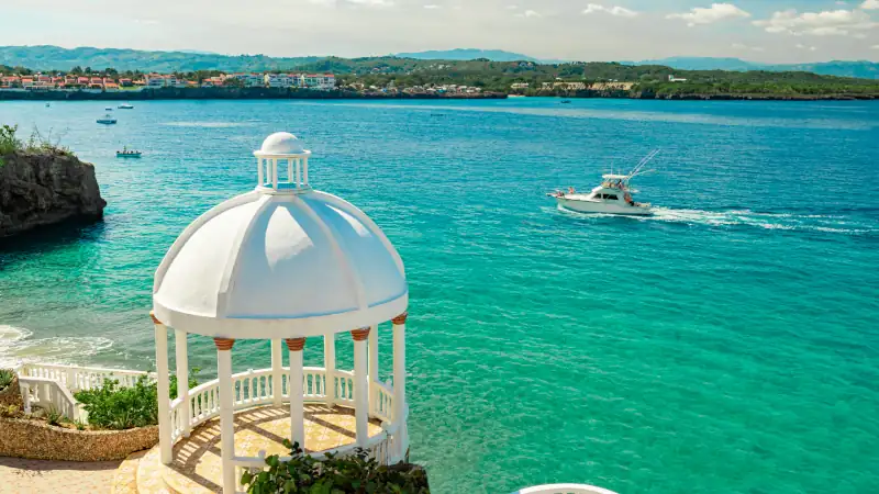 Beautiful white gazebo and tropical flower garden on Caribbean ocean background