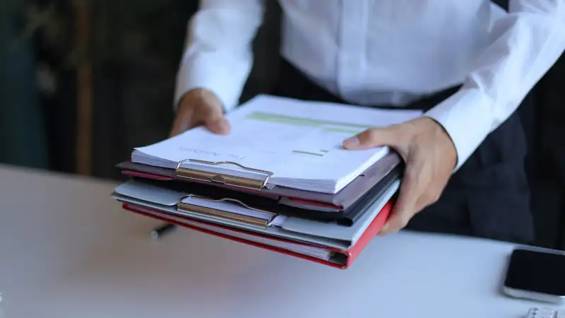 Businessman carrying stack of documents.
