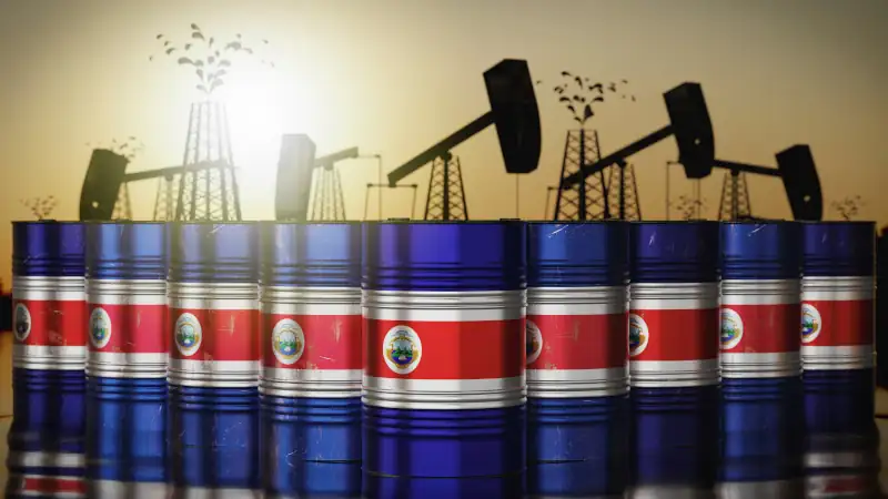 Costa Rica - many oil barrels with national flags, extraction wells in background
