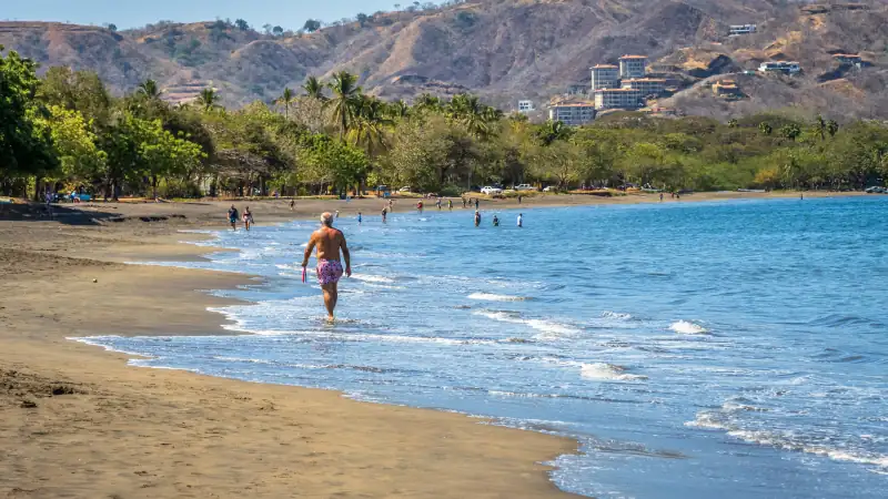 A peaceful image of a retired gentleman walking along the beach in Costa Rica