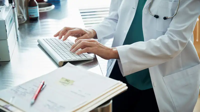 Doctor typing information on a keyboard