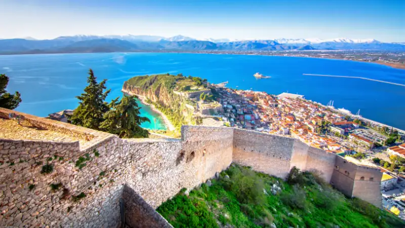 Old town of Nafplion in Greece view from above with tiled roofs, small port and bourtzi castle on the Mediterranean sea water