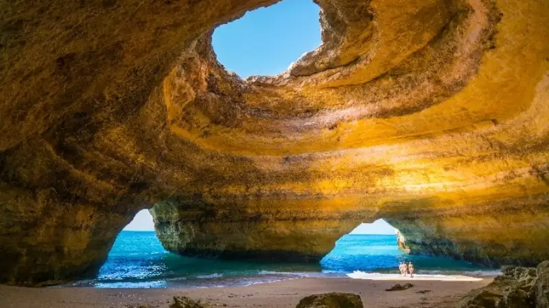 Benagil sea cave in Portugal, featuring golden rock formations, a natural skylight, and turquoise ocean waters.