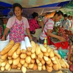 Venodrs selling food such as fruit and sandwiches in an open air market