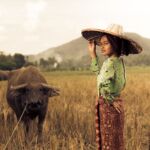 An Indonesian woman with a buffalo in a field