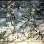 A stone wall with indonesian design carved into it