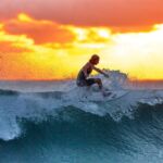 a srufer riding a wave at sunset in Indonesia