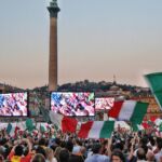 Italian football fans watch a game on outdoor screens.