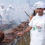 A chef in a white hat barbeques meat in traditional Uruguayan style.